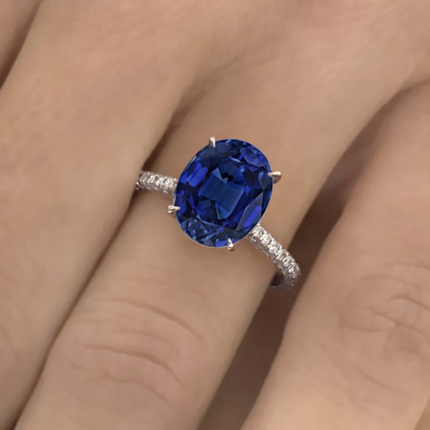 טבעת אירוסין רויאל – אבן ספיר כחולה אובלית במרכז, לצד יהלומים עגולים בשיבוץ צרפתי עדין